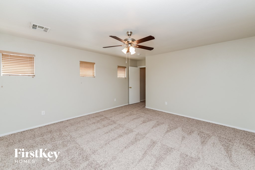 a spacious living room with carpet and a ceiling fan