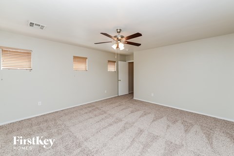 a spacious living room with carpet and a ceiling fan