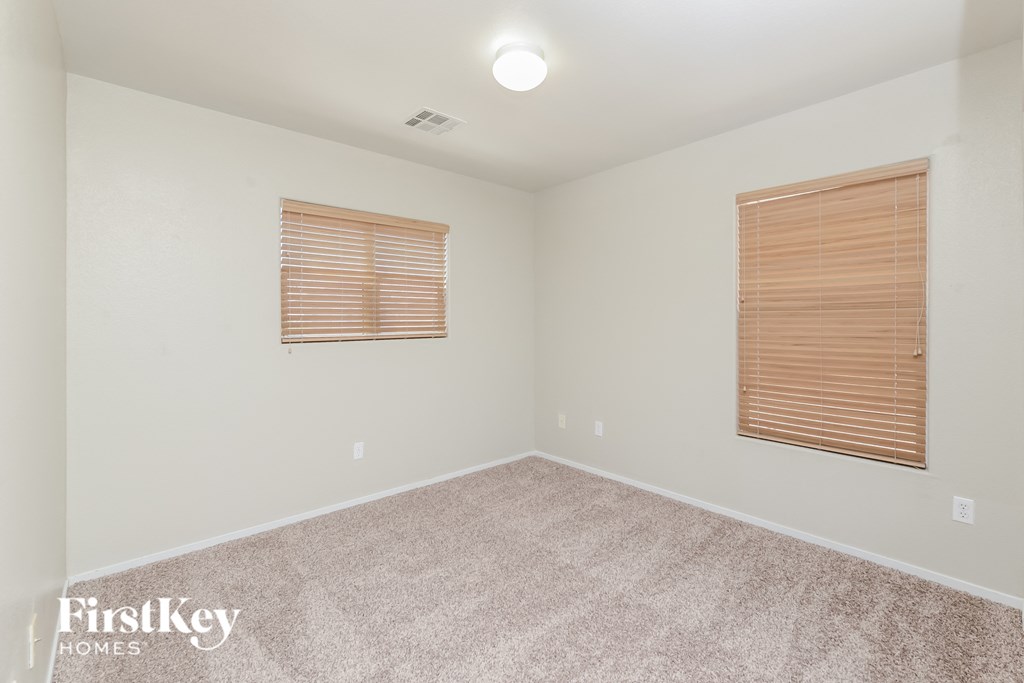 a spacious room with carpet and two windows
