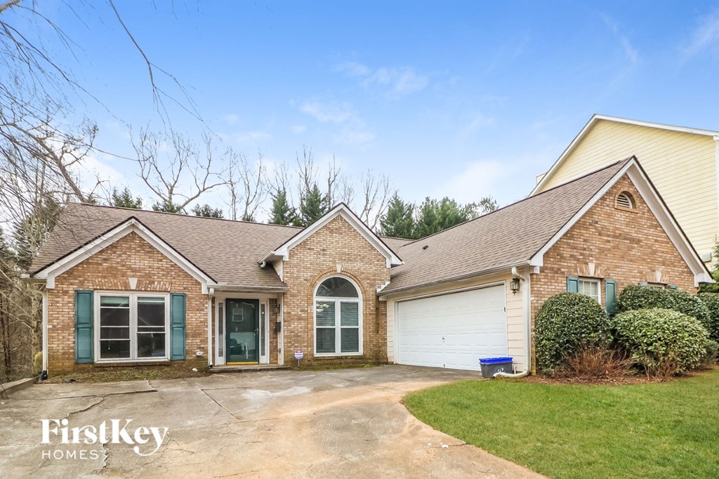 the front of a brick house with a driveway and a white garage door