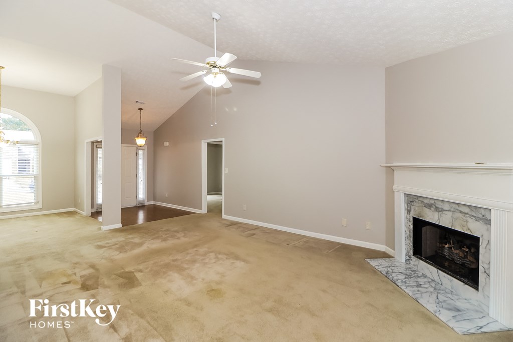 an empty living room with a fireplace and a ceiling fan