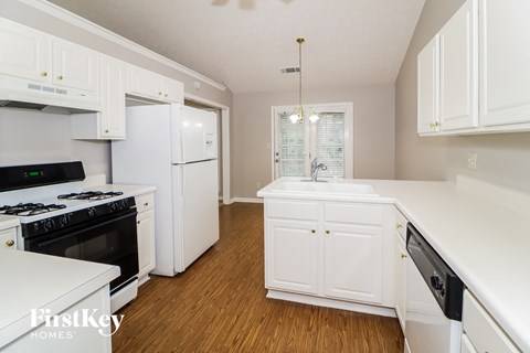 a kitchen with white cabinets and black appliances and a white sink