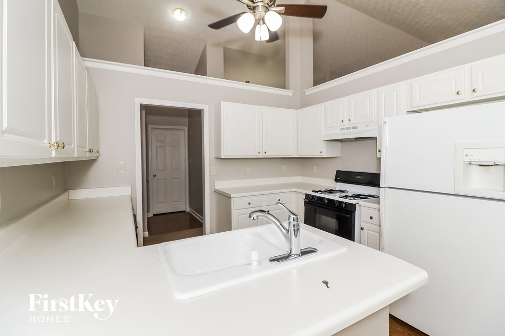 a kitchen with white cabinets and white appliances and a sink
