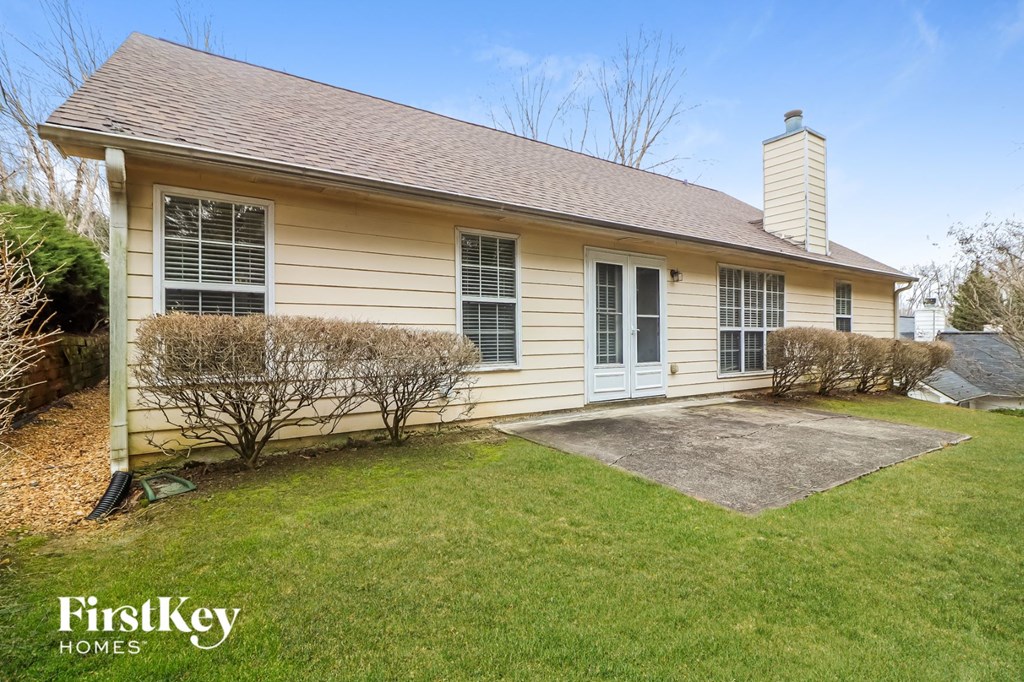 the front of a yellow house with a driveway and grass