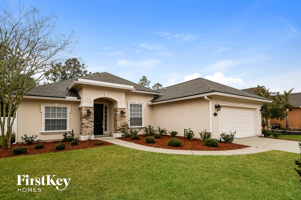a beige house with a lawn and a driveway