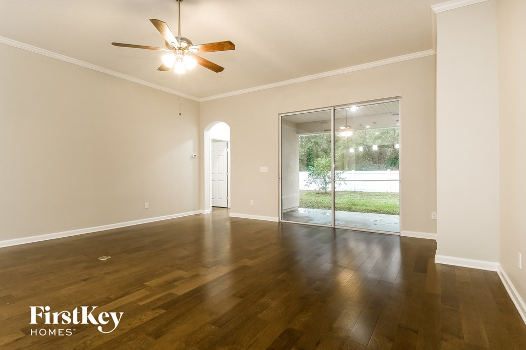 an empty living room with wood floors and a ceiling fan