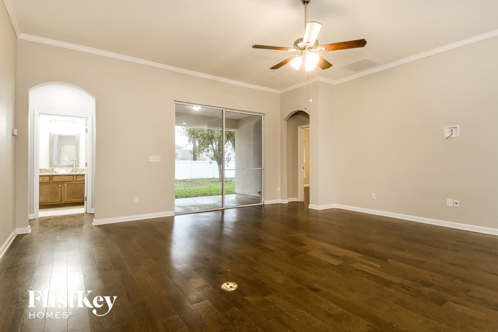 an empty living room with wood floors and a ceiling fan