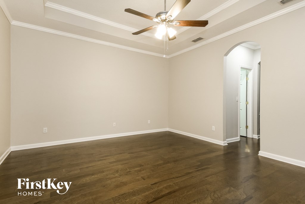 a empty living room with wood floors and a ceiling fan