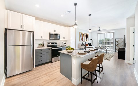 a large kitchen with stainless steel appliances and a large island with chairs