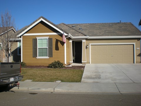 a yellow house with an flag on the driveway