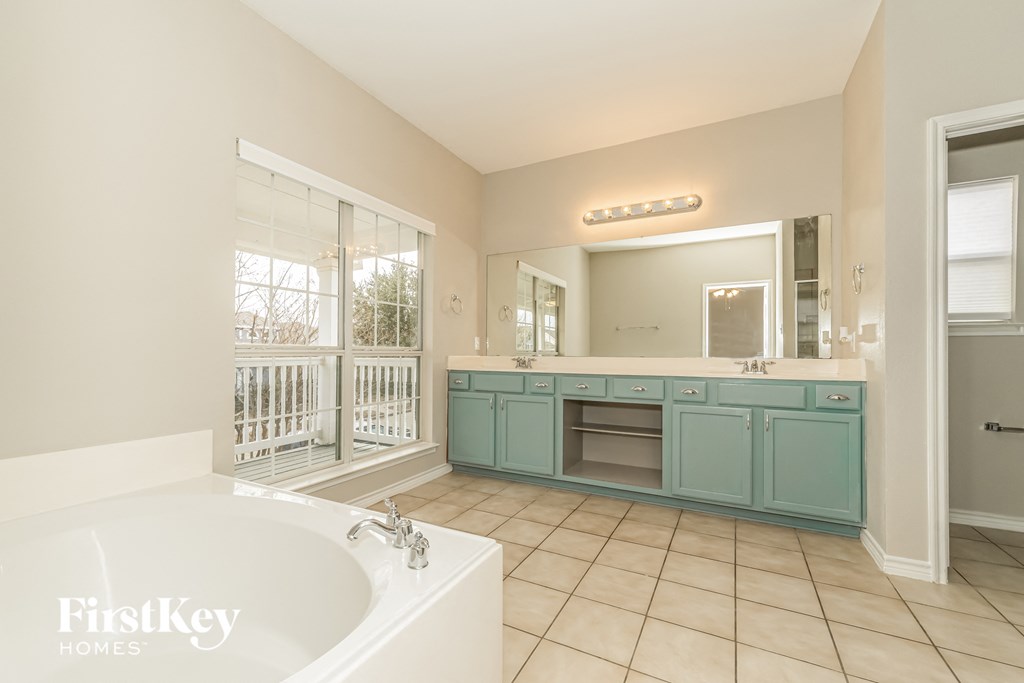 a large bathroom with a tub and a sink and a mirror