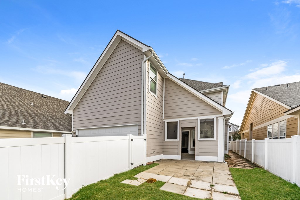 a gray house with a white fence and a yard