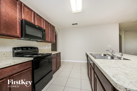 A kitchen with a black stove top oven and microwave above a black dishwasher.