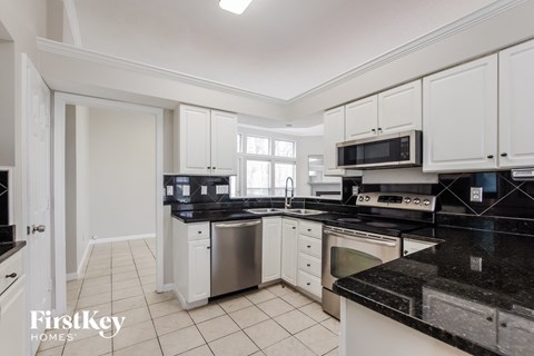 a kitchen with black counter tops and white cabinets and black and white appliances