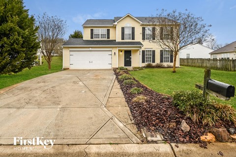 a yellow house with a driveway and a white garage door