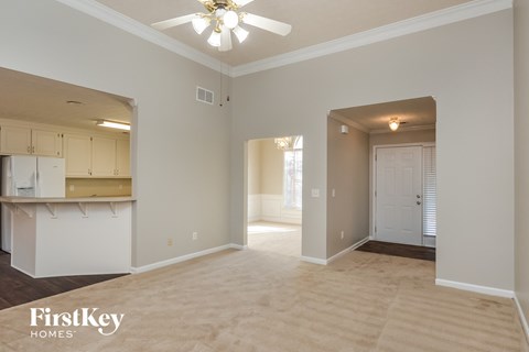 A spacious room with a kitchen area and a doorway leading to another room.