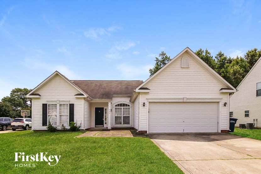A white house with a brown roof and a garage door.