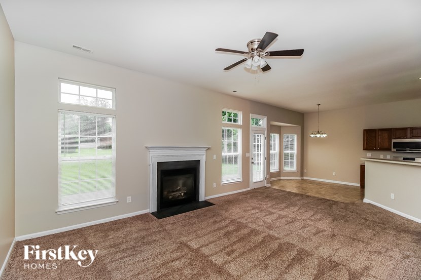 A spacious living room with a fireplace and a ceiling fan.