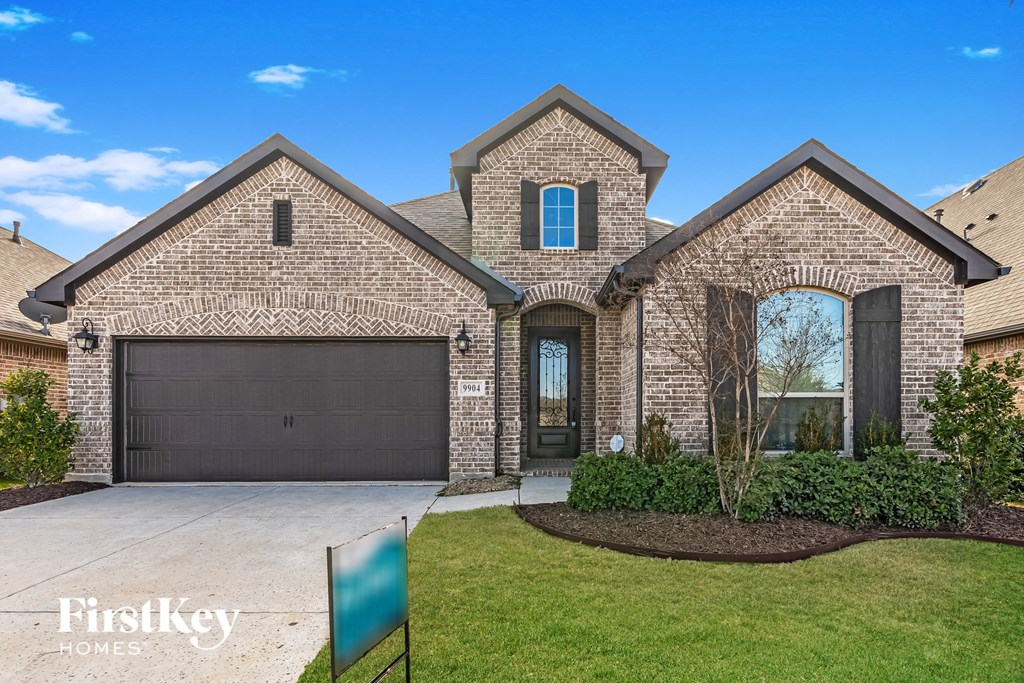 A brick house with a garage door and a sign that says FirstKey Homes.