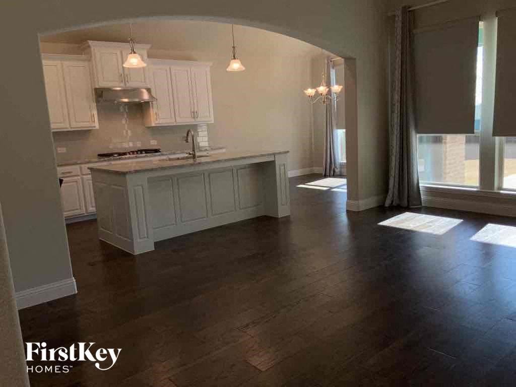 A kitchen with wooden floors and white cabinets.