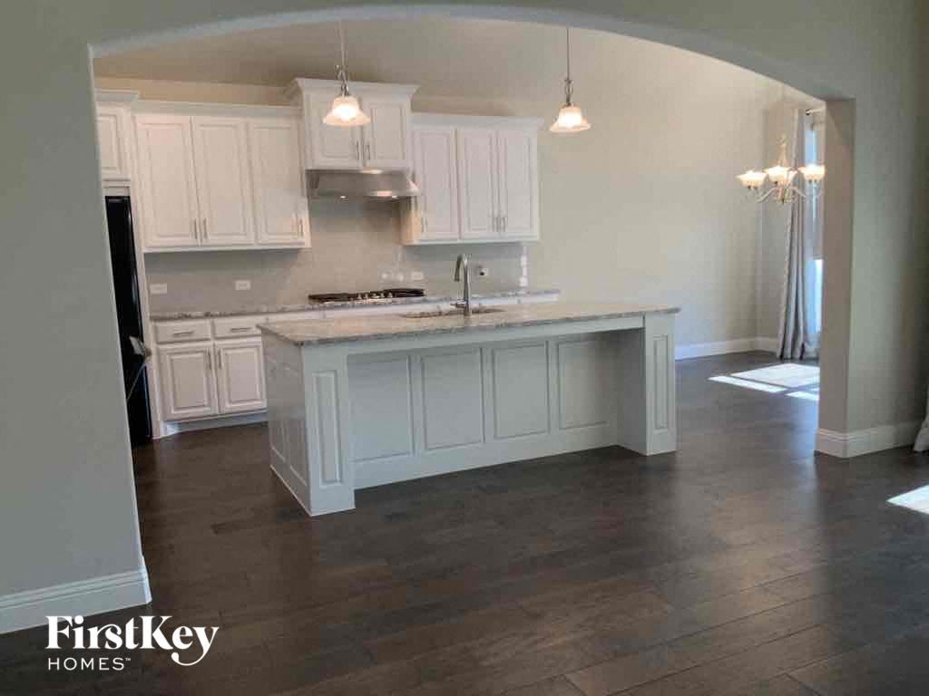 A kitchen with white cabinets and a wooden island.