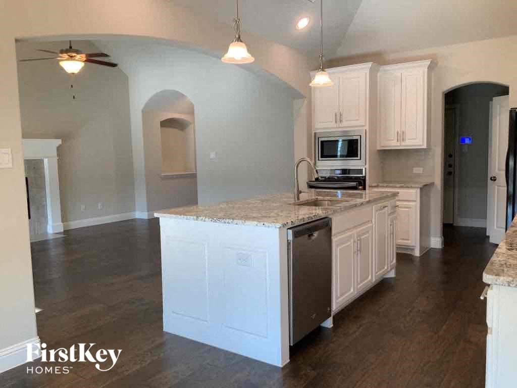 A kitchen with a granite countertop and a stainless steel dishwasher.