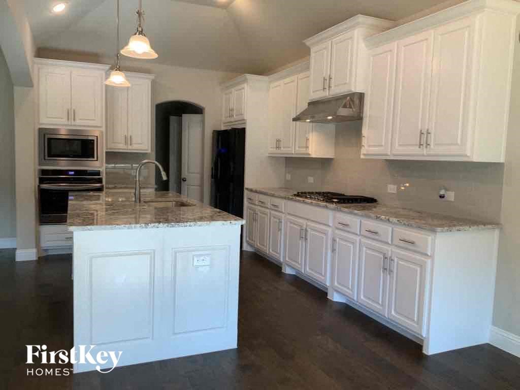 A kitchen with white cabinets and a marble countertop.