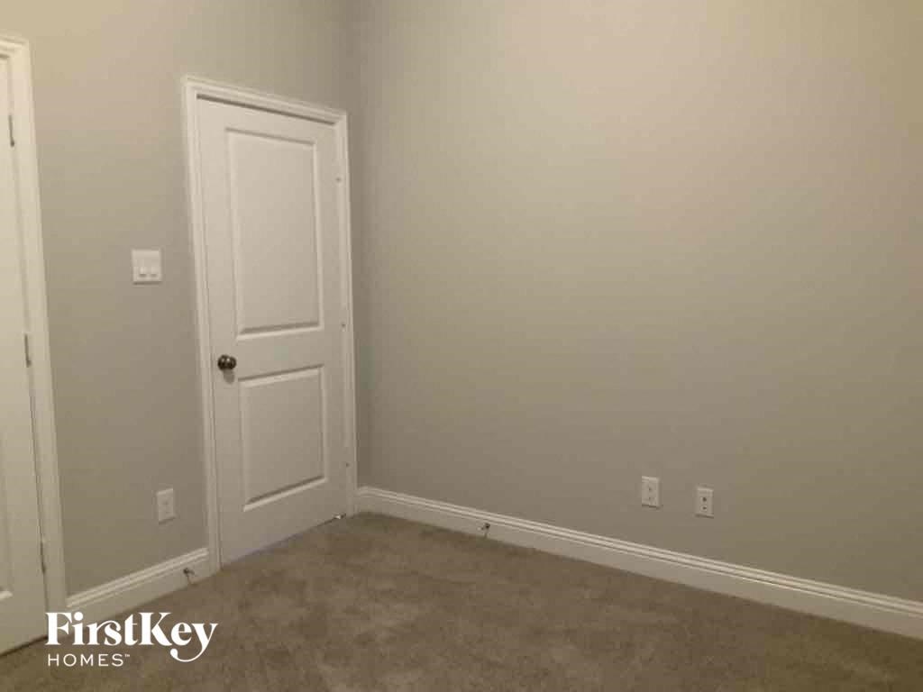 A room with a white door and a carpet floor.