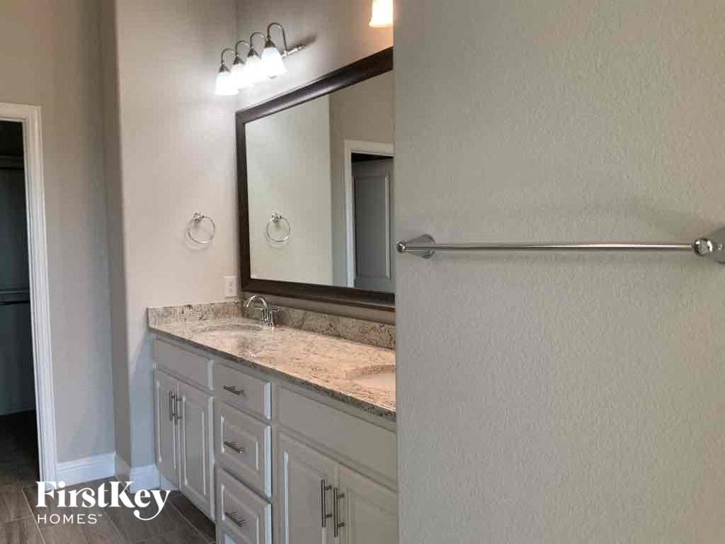 A bathroom with a mirror, light fixture, and a sink.