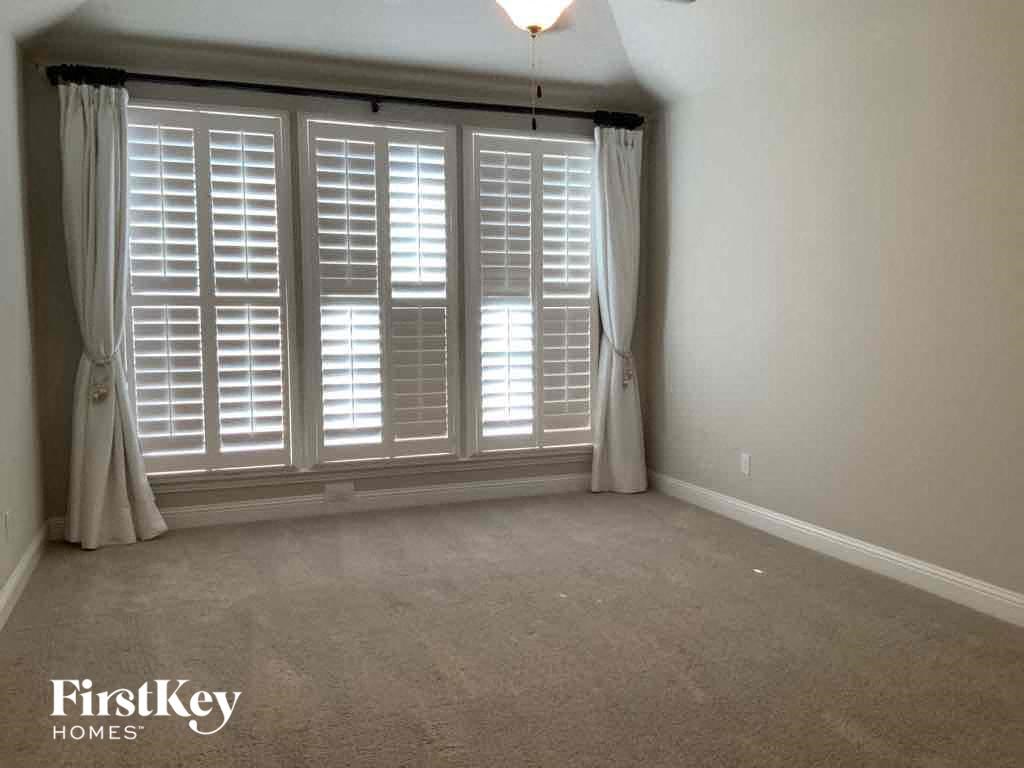 A room with a large window covered by white blinds and curtains.