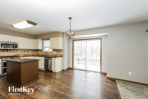 A kitchen with a brown island and a chandelier hanging from the ceiling.
