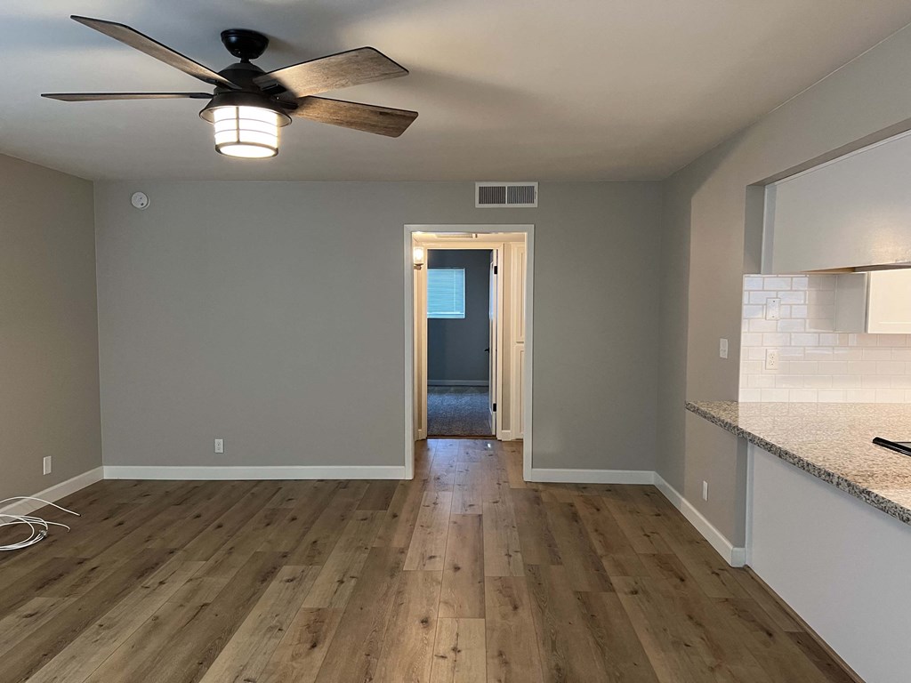 the view from the kitchen into the living room with a ceiling fan