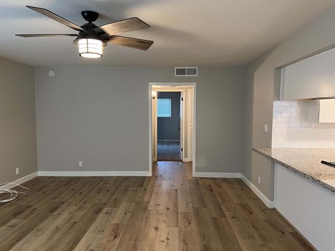 the view from the kitchen into the living room with a ceiling fan