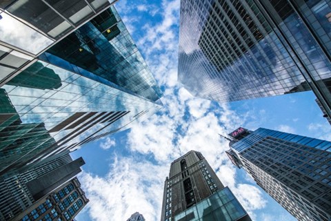 Skyscrapers reaching up to a blue sky with clouds.
