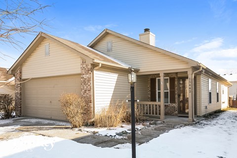 a home with a porch and a garage door in the snow