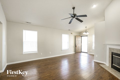 an empty living room with a ceiling fan and a fireplace