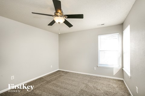 the spacious living room with carpet and a ceiling fan