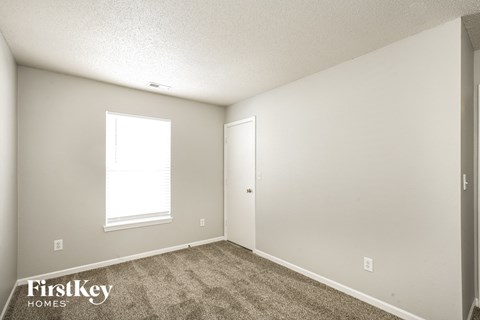 the living room of an apartment with carpet and a window