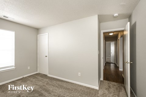 the living room and hallway of an apartment with a carpeted floor and a door