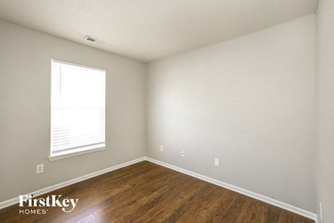 a bedroom with wood floors and white walls and a window