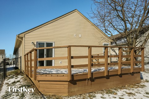 the outside of a house with a deck and a fence