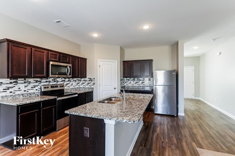 A kitchen with dark wood cabinets and granite countertops.