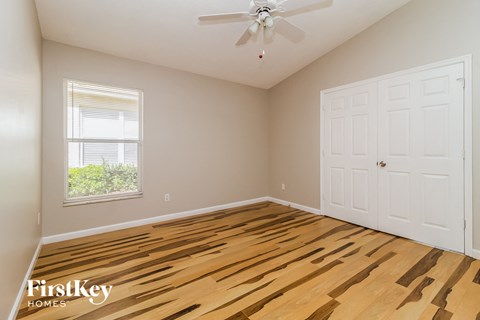 the second bedroom with hardwood flooring and a ceiling fan
