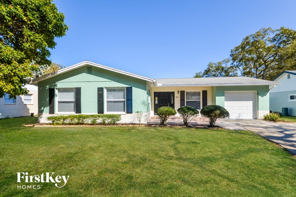 A house with a green front yard and a white garage door.