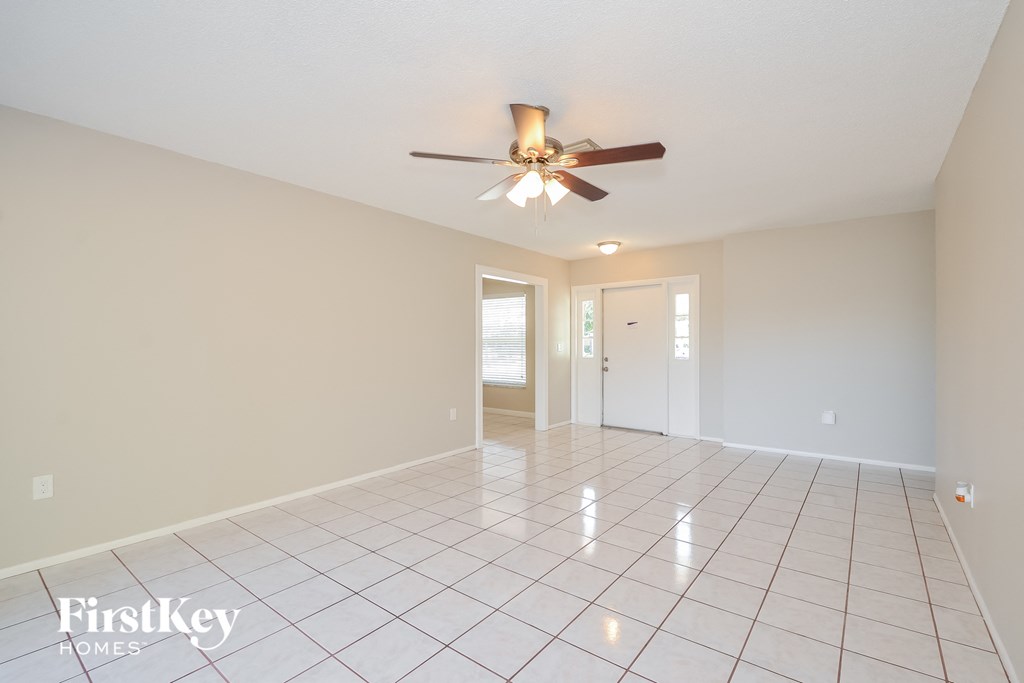 A spacious room with a ceiling fan and tile flooring.