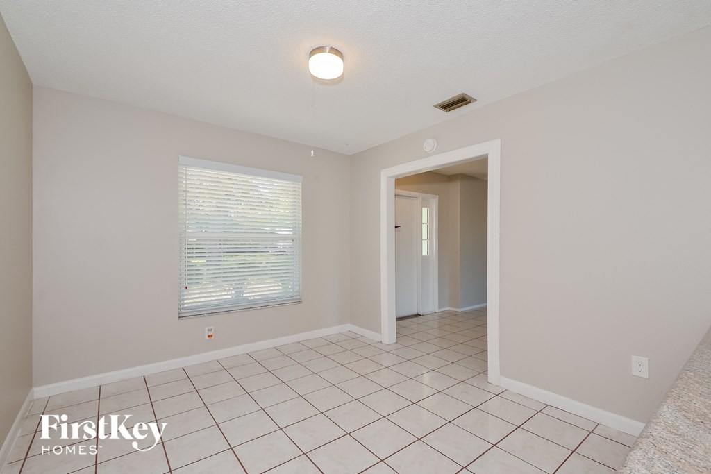 A spacious room with a tiled floor and a window with blinds.