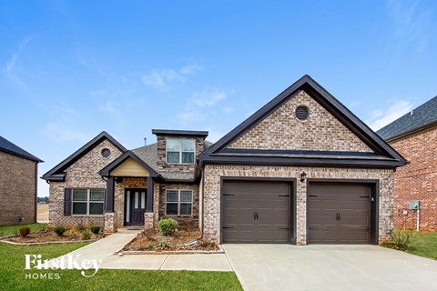 a home with two garage doors and a brick house