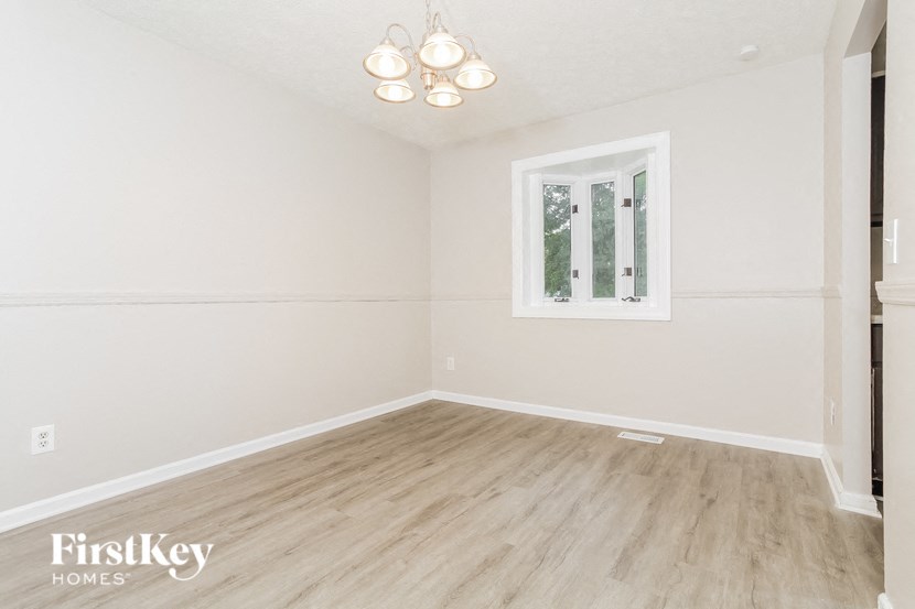 the living room of a home with white walls and a window