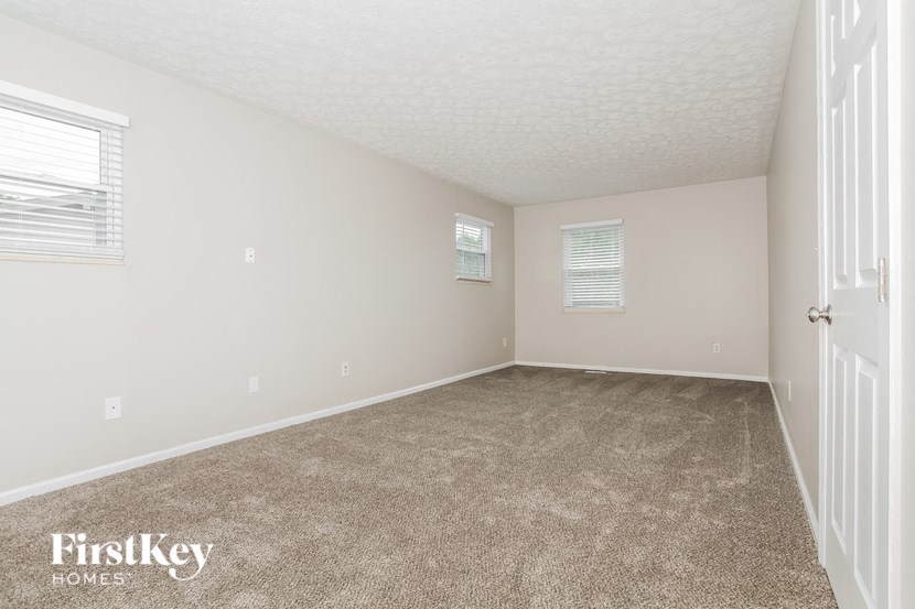 a spacious bedroom with carpeted flooring and white walls