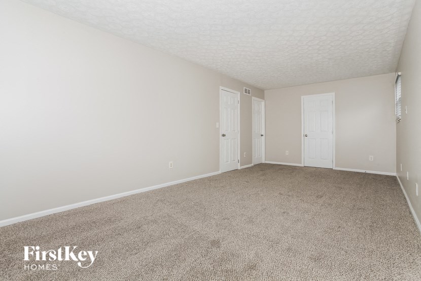 a spacious living room with beige carpet and white doors
